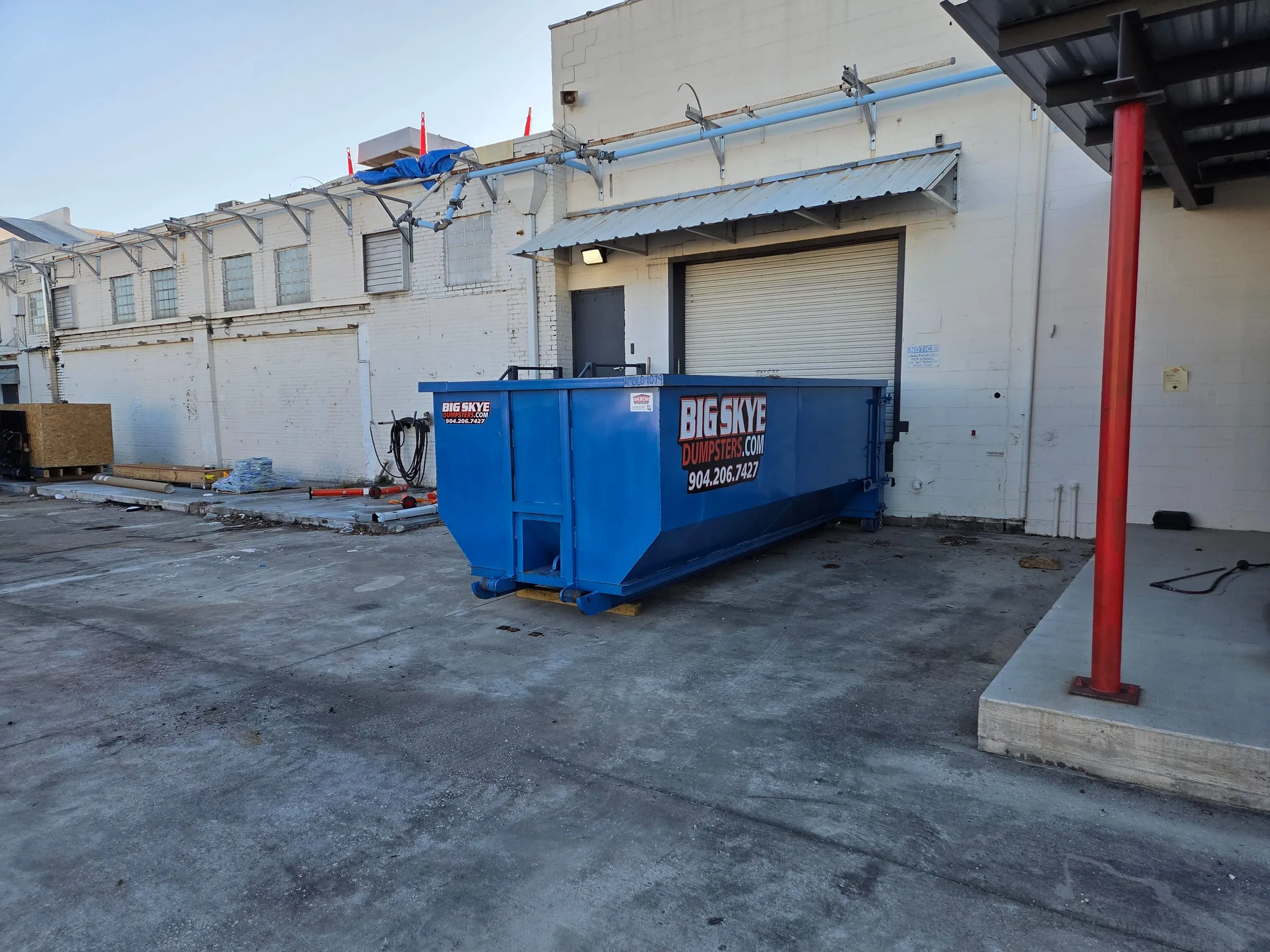 Big Skye roll-off dumpster at a commercial building loading dock