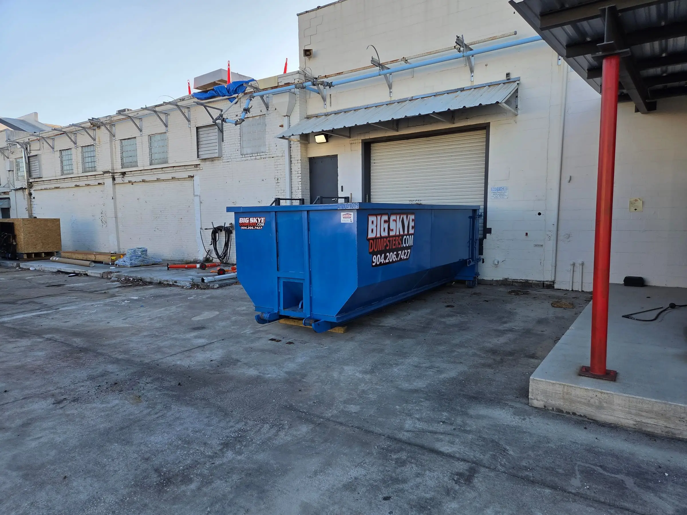 Big Skye roll-off dumpster at a commercial building loading dock